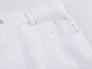 Detailansicht der weißen Denim-Shorts mit Hohlstickerei und dekorativem Metallknopf