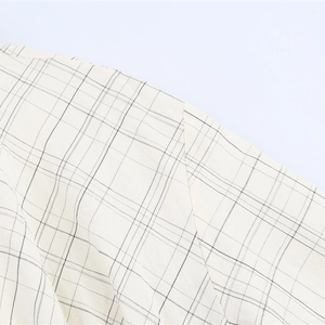 Women's plaid bomber shirt jacket in beige and black check fabric close-up view