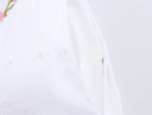 Gros plan sur tissu en coton blanc avec broderie florale délicate et détails ajourés