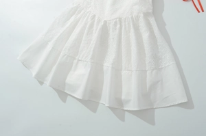 Détail du tissu en dentelle blanche avec broderie florale et coutures à plusieurs niveaux