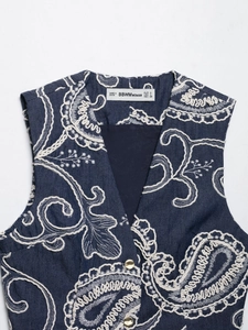 Detail of navy blue sleeveless vest with white floral embroidery and gold buttons