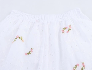 Détail du short élastique en coton brodé blanc avec broderie de fleurs roses délicates