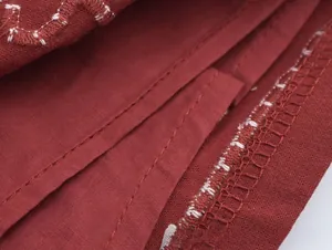 Détails de couture surjet bicolore sur la texture du tissu rouge foncé de la jupe
