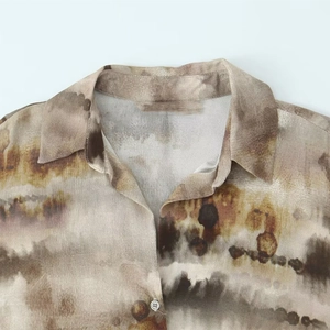 Detailed macro view of the lapel collar and abstract ink-wash pattern on silk-like fabric