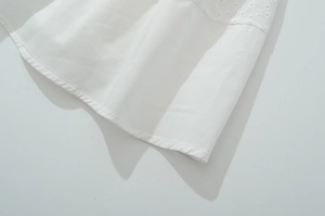 Détails d'une robe en dentelle blanche avec broderie florale ajourée sur l'ourlet