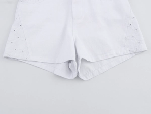 Detailansicht weißer Denim-Shorts mit aufwendiger Lochstickerei und Wellenmustern
