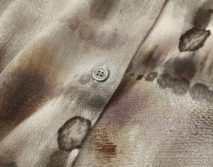 Detail of artistic ink-wash print fabric and high-quality button on a casual shirt