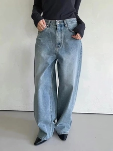 Detail view of high-waisted wide-leg denim jeans in light blue wash with metal button