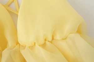Dettaglio dell'abito giallo pallido con scollo a V, spalline sottili e tessuto in chiffon