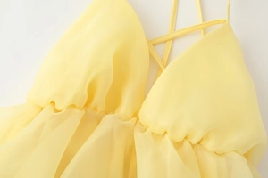 Dettaglio dell'abito in chiffon giallo con profondo scollo a V e dettagli pieghettati