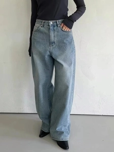 Detailed view of high-waist loose jeans with vintage washing and cat whisker texture