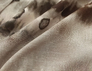 Macro detail of silky tie-dye fabric with smooth texture and earthy brown tones