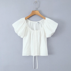 Détail de blouse blanche à manches bouffantes avec dentelle et boutons verticaux