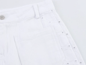 Detail der weißen Jeans-Shorts mit Metallknopf und kreisförmigen Stickerei-Ausschnitten