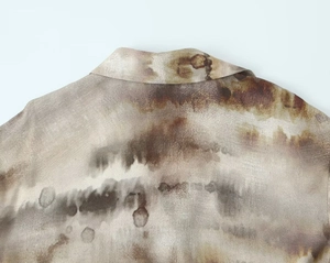 Macro detail of Earth-toned tie-dye fabric on lapel shirt with artistic ink texture