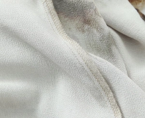 Detailed macro view showing professional overlock stitch on tie-dye shirt fabric