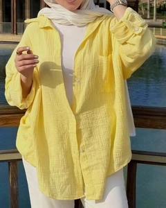 Detail of yellow cotton linen shirt featuring textured crinkle fabric and button pocket