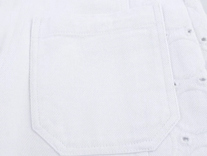 Detailansicht der weißen Denim-Tasche mit eleganter runder Lochstickerei und Steppnaht