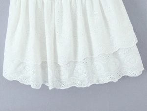 Dettaglio del ricamo bianco Broderie Anglaise sull'orlo a balze di un abito estivo
