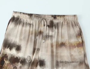 Detail of elastic high waist on tie-dye trousers with drawstring and metal tips