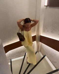 Close-up of pale yellow pleated camisole and maxi skirt set with cotton linen texture