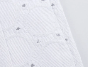 Nahaufnahme von weißem Hohlstickerei-Stoff mit feinen kreisförmigen Texturmustern