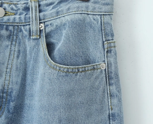 Detailed macro view of denim jeans waist featuring dual stitching and metal rivets