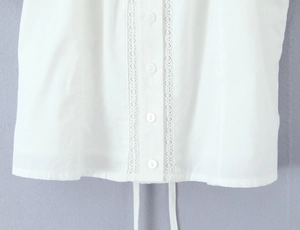 Détail du haut blanc avec bordure en dentelle, boutons et cordon de serrage à l'ourlet