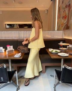 Detail of pale yellow summer set featuring pleated strappy top and matching midi skirt