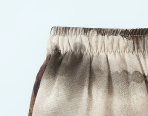 Detail shot of the elastic waist band on women's marble tie-dye trousers with silky fabric
