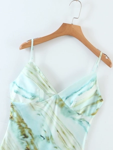 Détail d'une robe en satin avec imprimé marbré vert et fines bretelles réglables