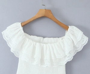 Dettaglio del top bianco a spalle scoperte con scollatura a punto smock e pizzo