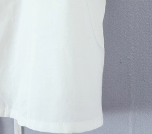 Gros plan des coutures et de la texture du tissu sur une blouse blanche à manches