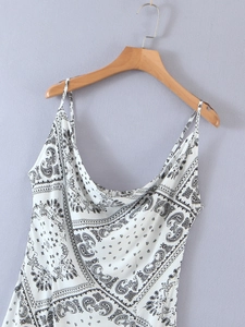 Detailed view of the draped cowl neckline and black paisley print on a white summer dress