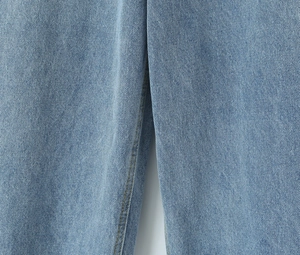 Detailed close-up showing light blue denim fabric texture and reinforced double stitching