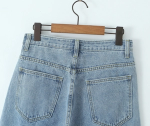 Detail view of high-waist light blue denim jeans with back pockets and belt loops