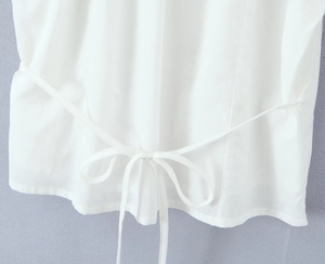 Détail d'un haut blanc avec manches bouffantes délicates et un nœud élégant à la taille