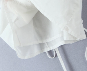 Gros plan du haut blanc à manches bouffantes montrant les coutures et le cordon
