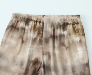Detail view of elastic waist on tie-dye casual pants with bohemian brown abstract patterns