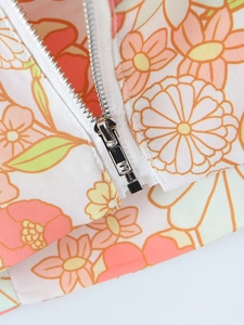 Dettaglio di una cerniera in metallo argento su tessuto di chiffon a fiori estivo