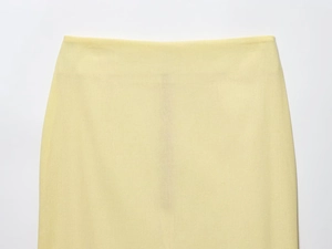 Detail of high-waist pale yellow skirt showing fine woven texture and tailored waist cut
