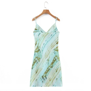 Détail d'une robe en satin tie-dye vert clair avec col en V sur un cintre en bois