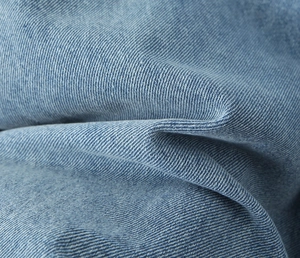 Macro shot of light blue denim fabric texture with twill weave and natural wash effect