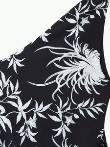 Gros plan détaillé d'une broderie florale blanche sur une robe d'été noire asymétrique