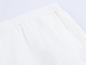 Detail of white pajamas shorts featuring elastic waistband and fine pleated stitching