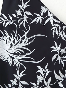 Gros plan sur la broderie florale blanche complexe sur le tissu d'une robe d'été noire