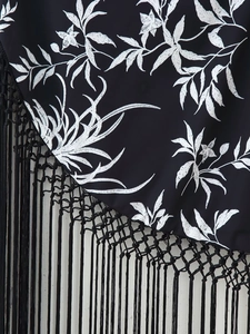 Détail de robe noire avec broderie blanche et ourlet à franges bohème