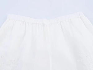 Close-up of elastic waistband on white cotton shorts with delicate floral embroidery detail