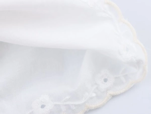 Close-up of white floral hollow embroidery with scalloped edges on elegant summer top