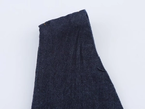 Detailed macro view of dark blue denim fabric texture with orange contrast stitching